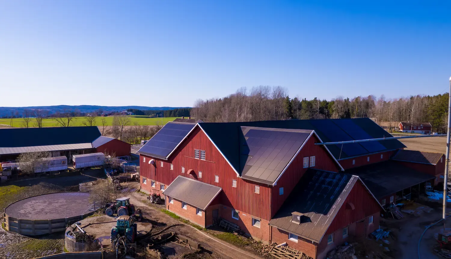 Dronefoto av en rød norsk låve med solcellepaneler over hele taket