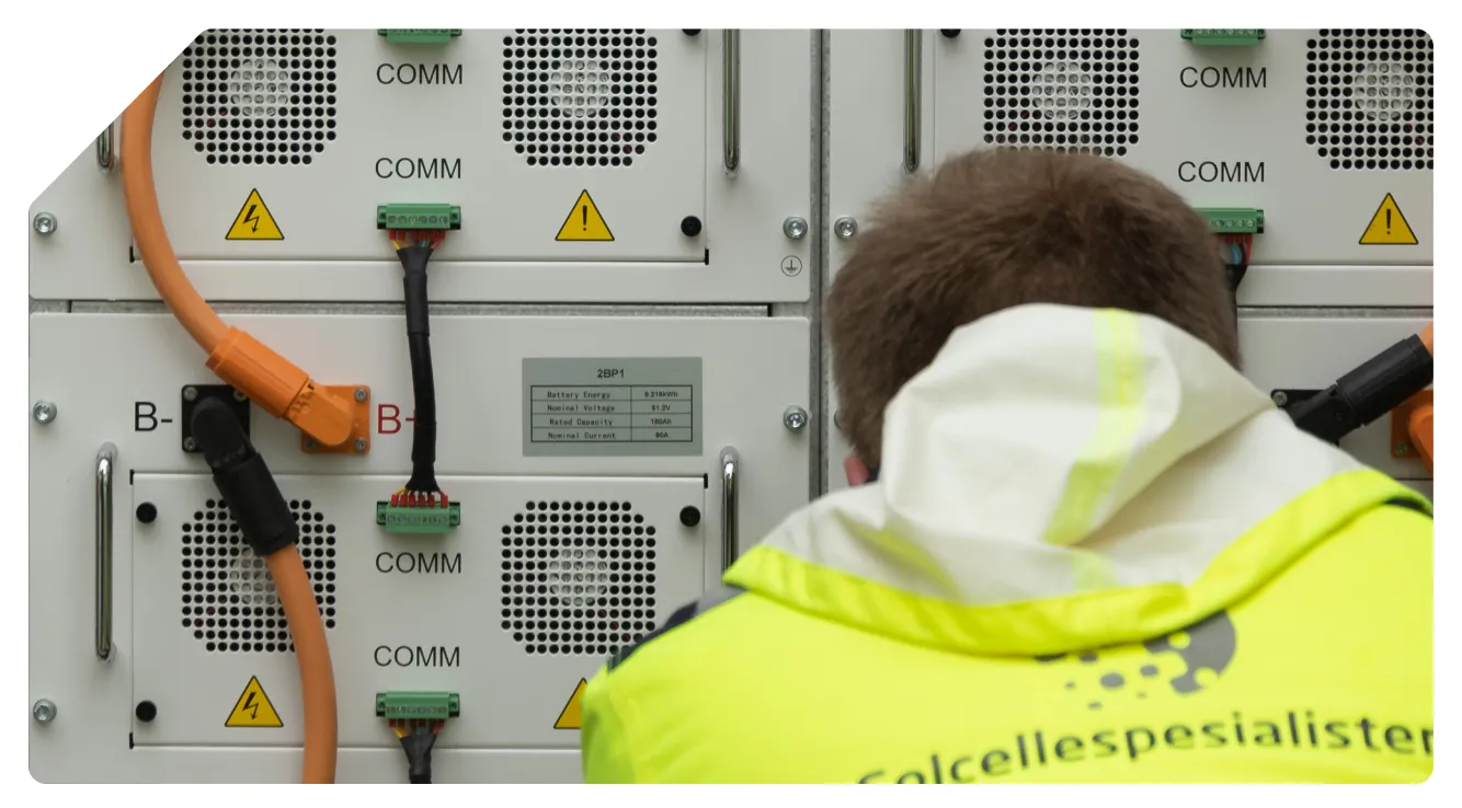 Montør fra Solcellespesialisten som arbeider med kabling i et batteriskap for energilagring