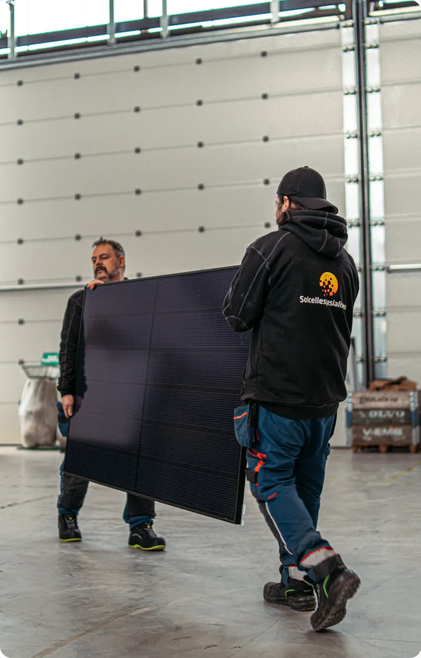 Two installers carrying a solar panel across a site