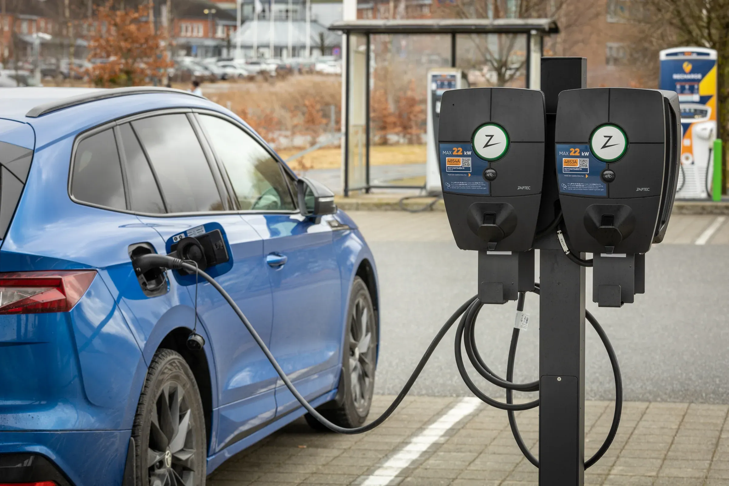 To ladestasjoner på en parkeringsplass, den ene lader en elbil
